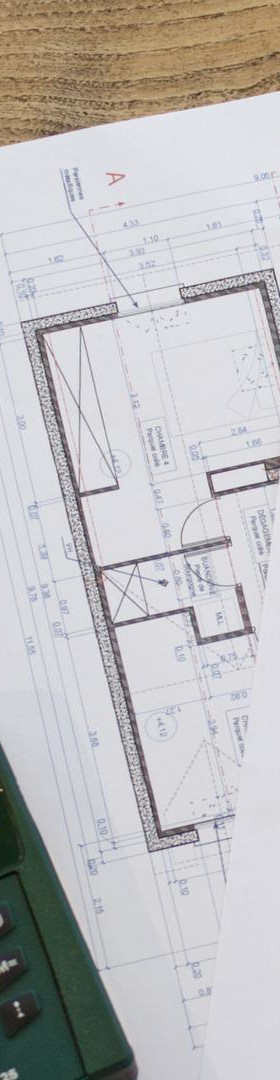 住宅新築設計図面と計算機が置いてある机の細い縦型画像